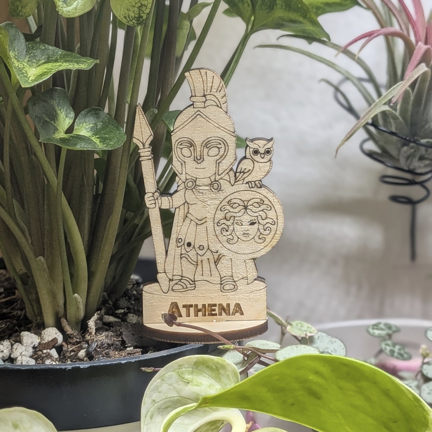 Athena goddess of laser cut plywood in a plant pot. Features a helmet, spear, and detailed owl shield on a round wood base