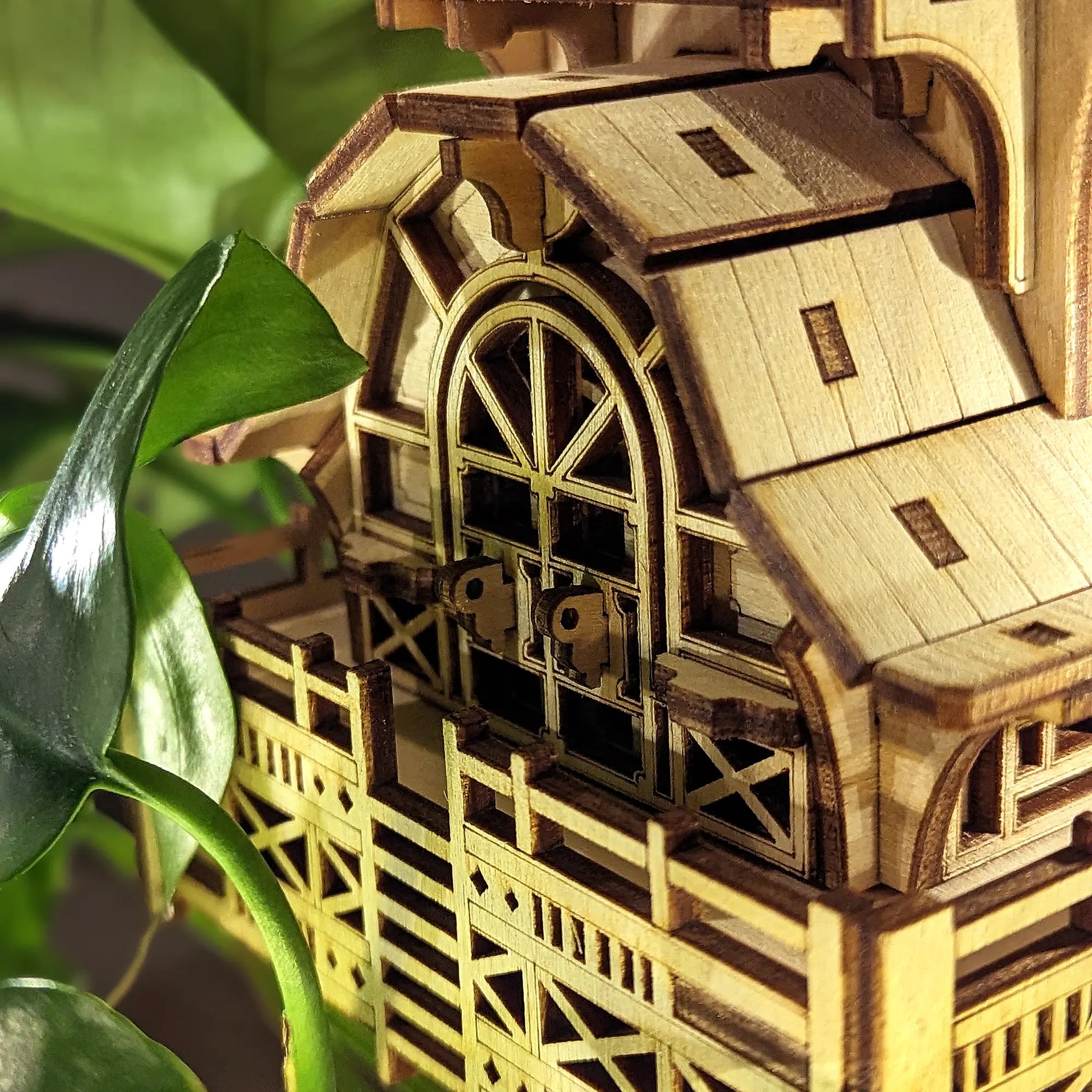 Macro view of an arched balcony door with small latches on a miniature house made from laser cut plywood panels.