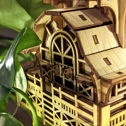 Macro view of an arched balcony door with small latches on a miniature house made from laser cut plywood panels.