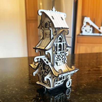 Miniature fantasy caravan wagon made of laser cut plywood with detailed stairs and flower box on a white background.