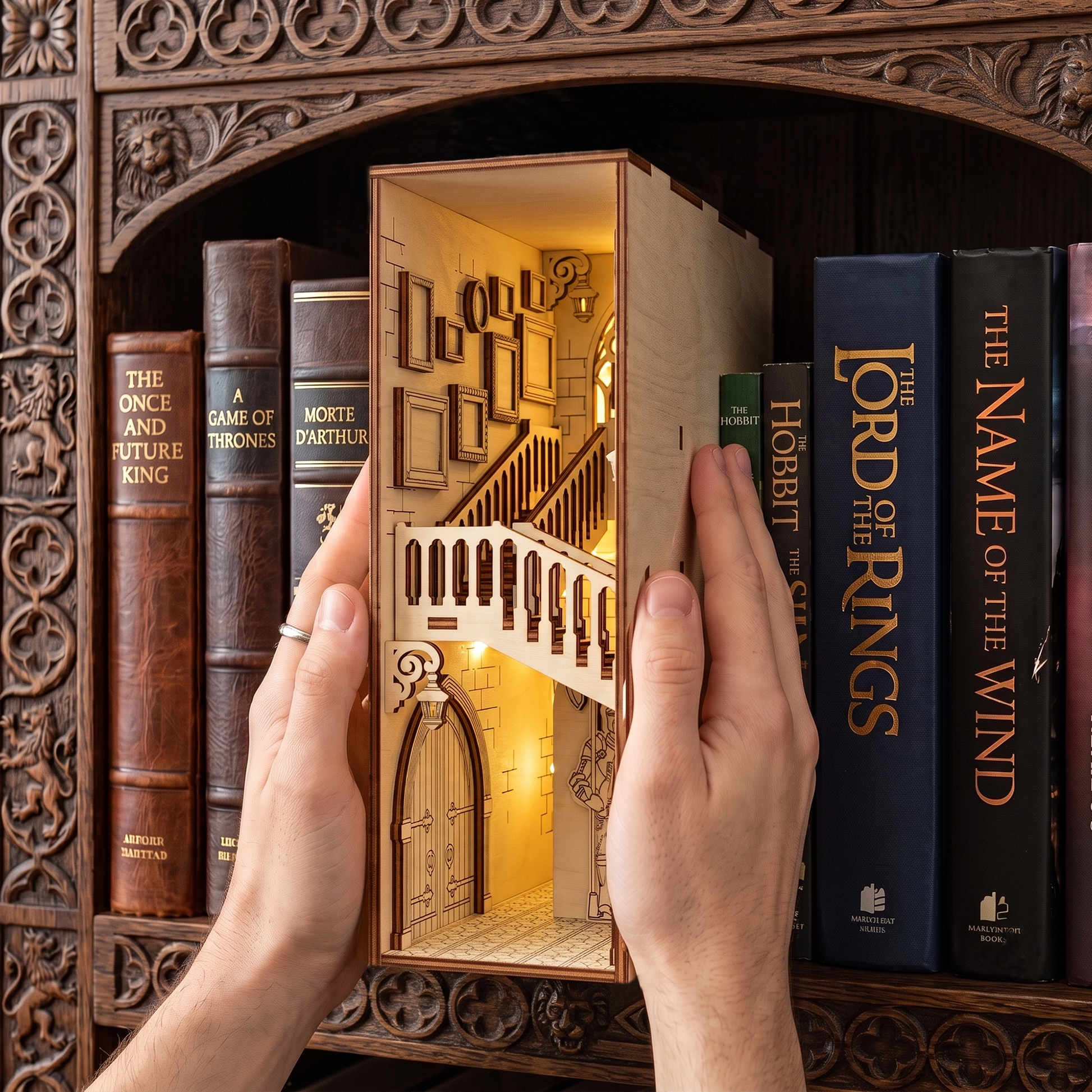Hands holding a lit laser-cut birch plywood castle book nook on a shelf between fantasy books, with warm internal lights