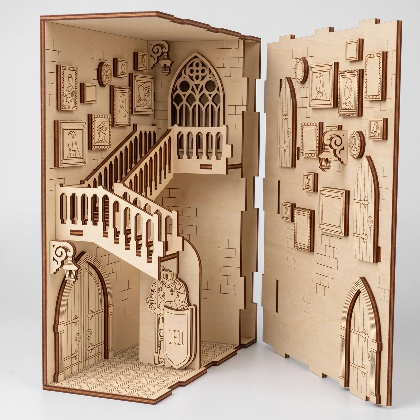 Open view of a laser-cut birch plywood castle book nook showcasing stairs, wall frames, and a knight figure with dark burnt edges.