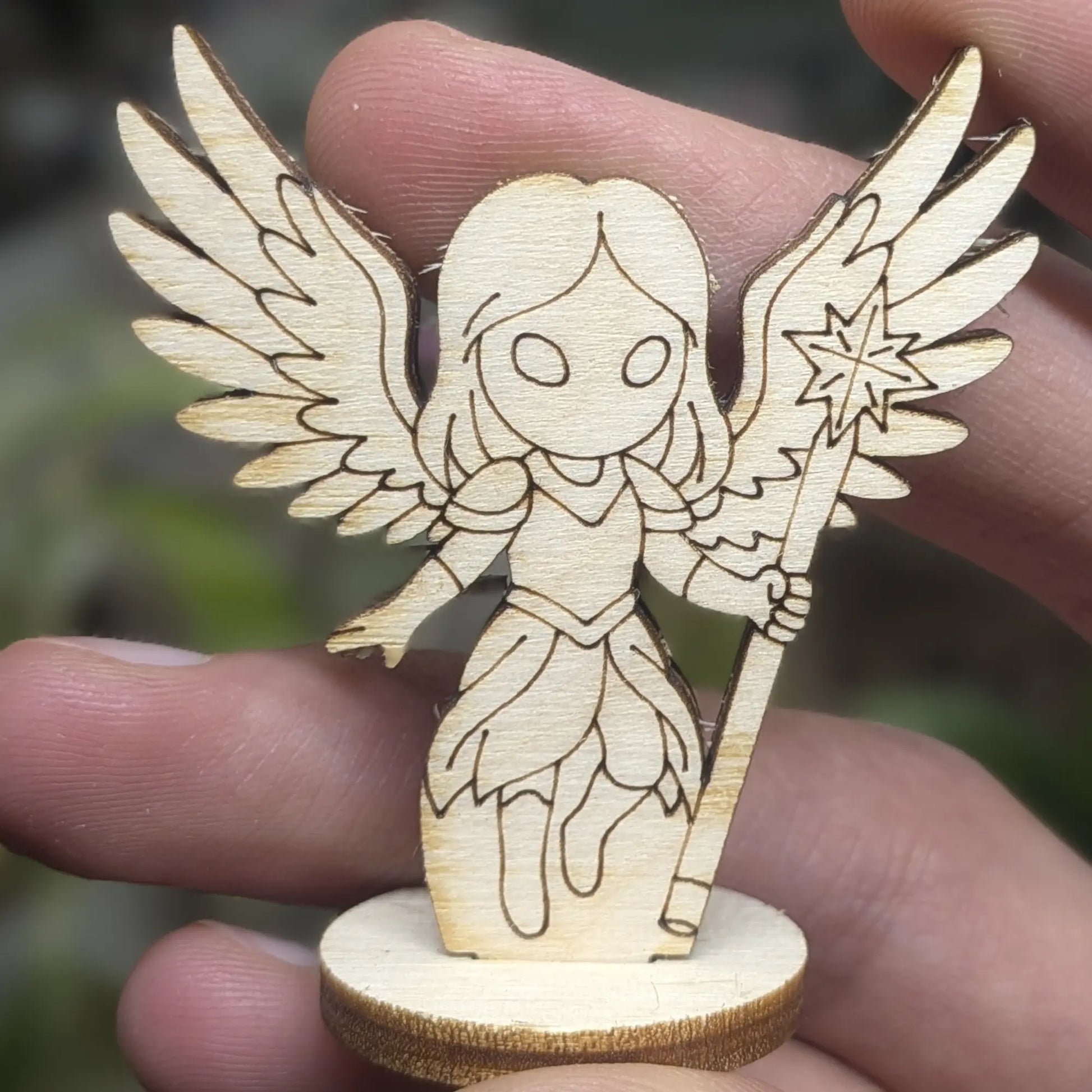 Hand holds a laser cut plywood celestial angel for scale. Detailed front view showing the engraved halo and wing patterns