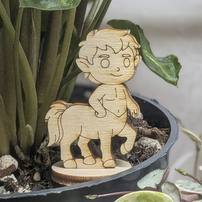 Centaur miniature of laser cut plywood in a plant pot. Features a human torso, horse body, and detailed wood grain texture