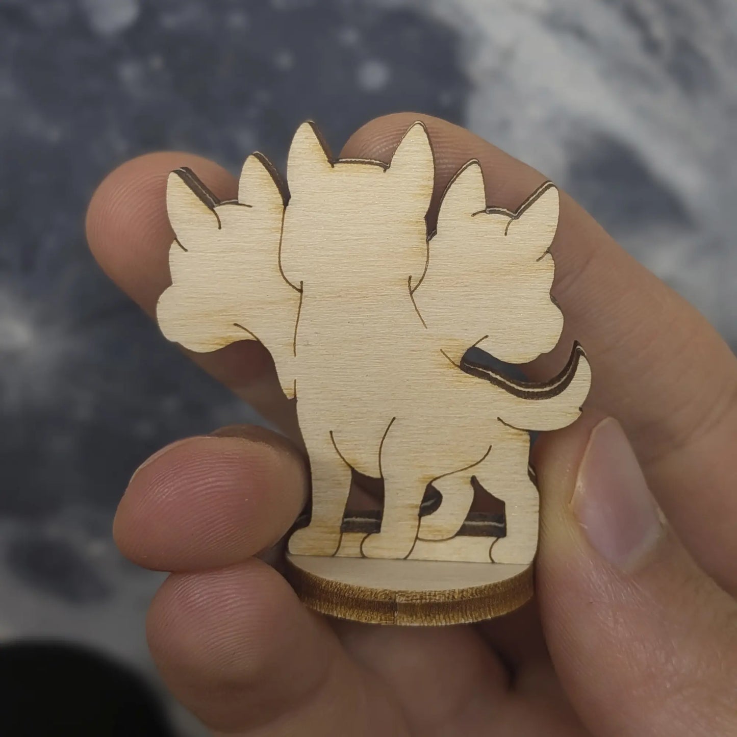 Laser cut plywood Cerberus figurine stands in a plant pot, featuring three detailed heads with engraved facial expressions