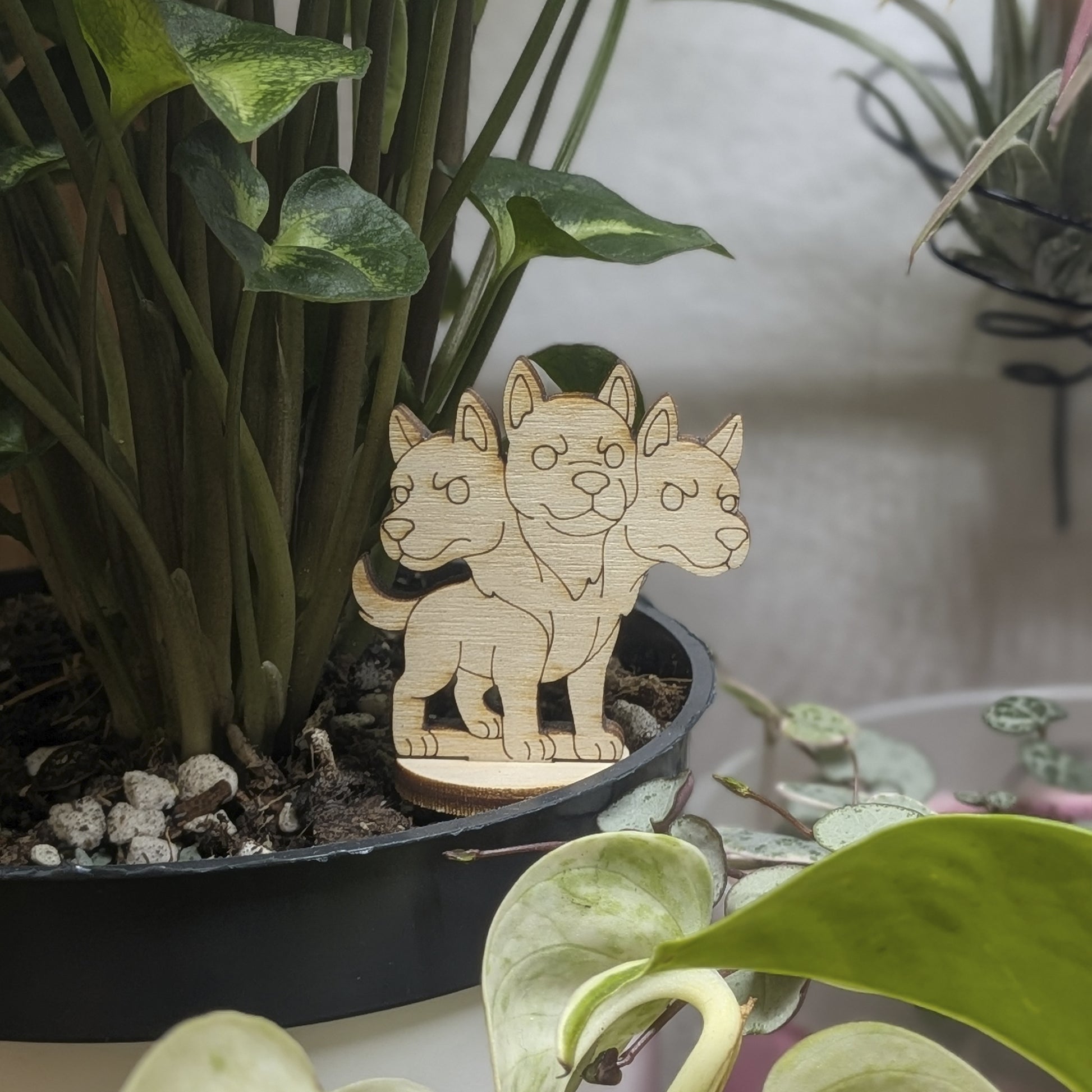 Back view of a laser cut plywood Cerberus held in hand, showing light wood grain, dark burnt edges, and smooth texture