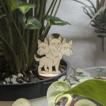 Back view of a laser cut plywood Cerberus held in hand, showing light wood grain, dark burnt edges, and smooth texture