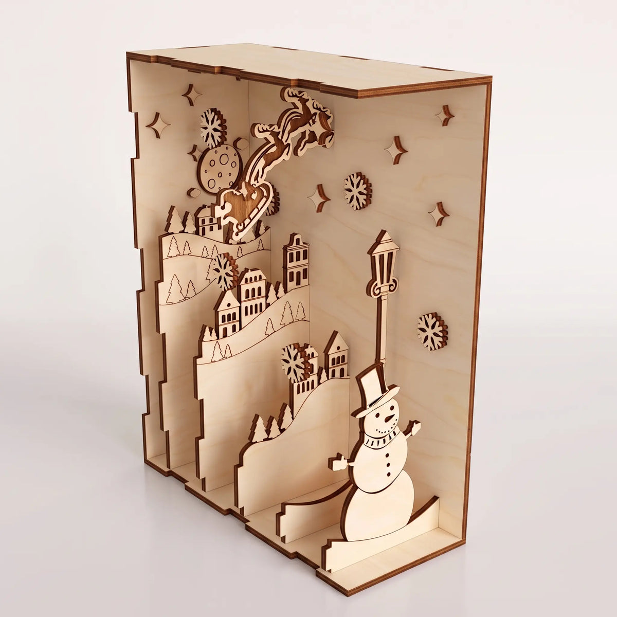 Right perspective view of layered laser cut plywood book nook showing snowman, Santa sleigh, and village on white.