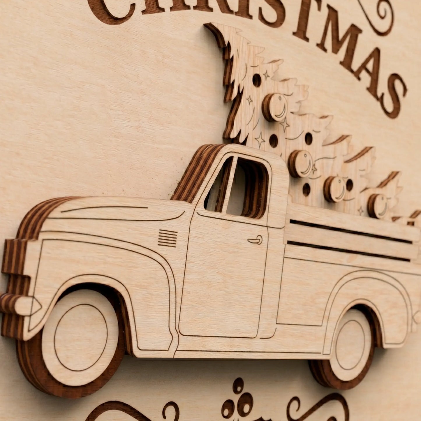 Close up of a laser cut plywood holiday sign showing 3D layered vintage truck carrying a detailed Christmas tree.