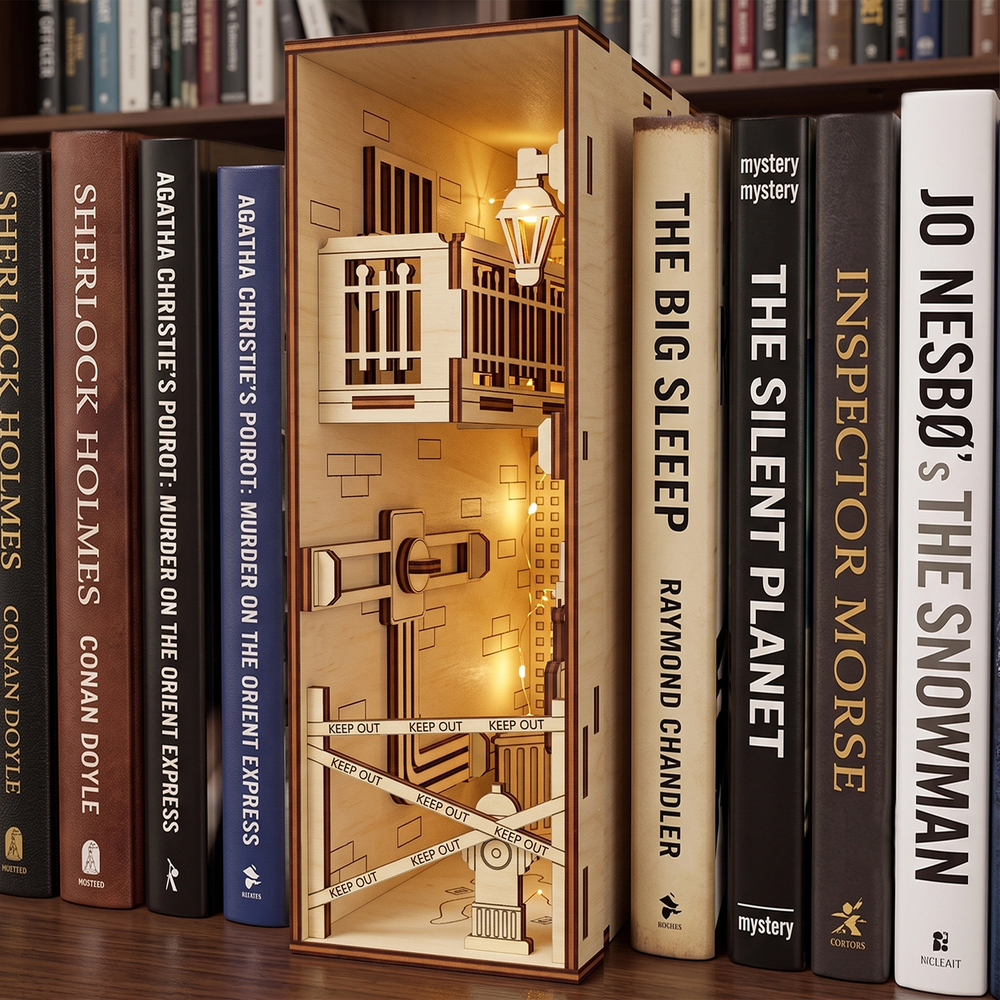 Lit laser-cut birch plywood crime scene book nook on a shelf between mystery books, featuring warm internal lights.
