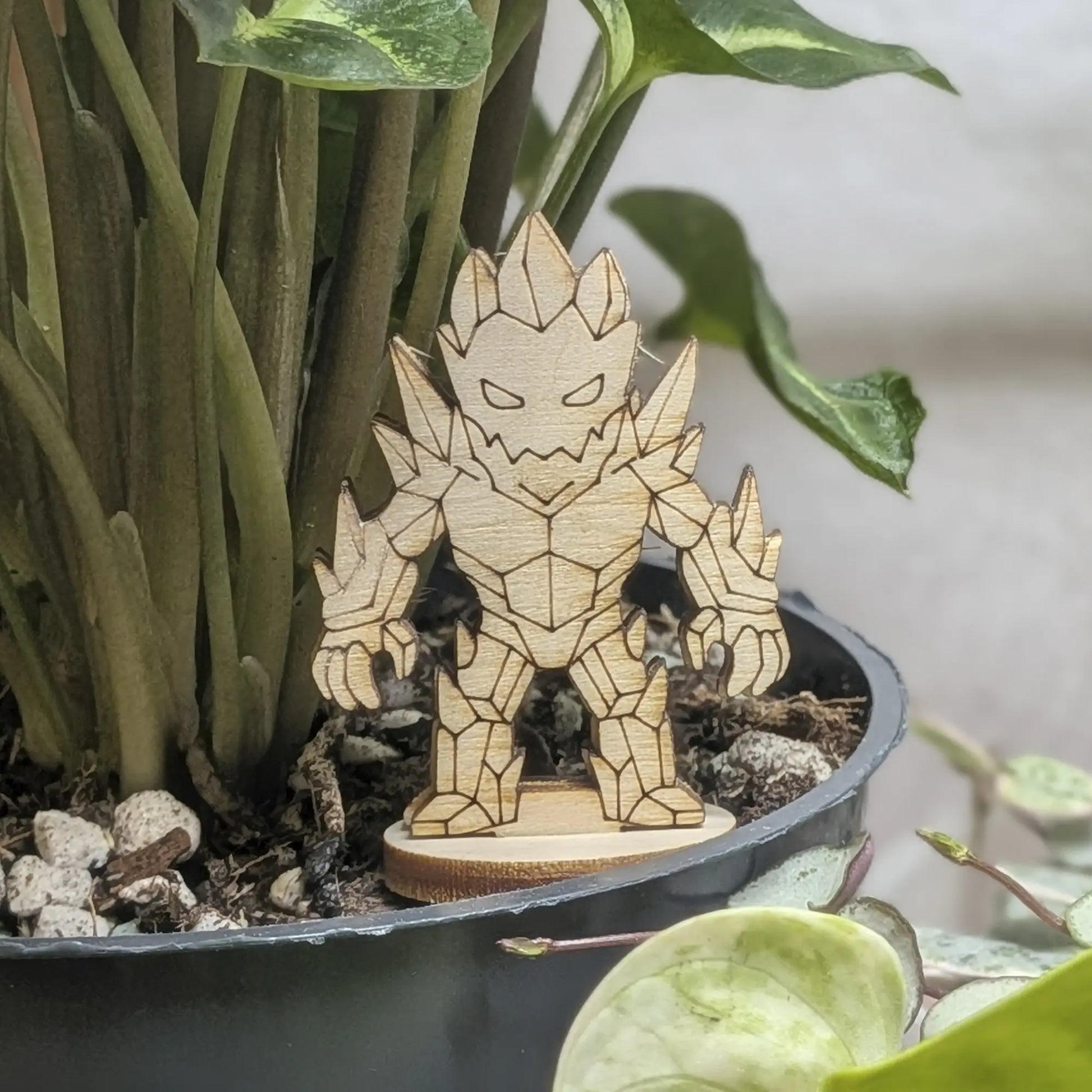 A crystal golem miniature of laser cut plywood stands in a black plant pot. Features sharp faceted crystal shards and spikes