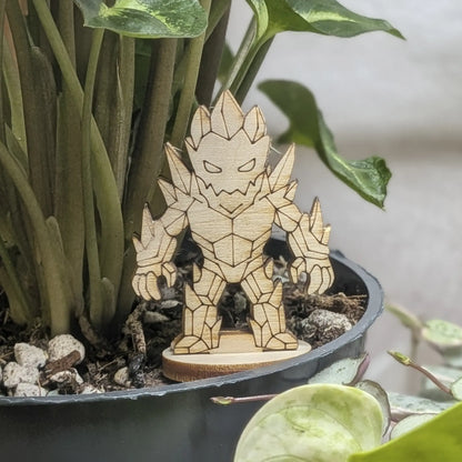 A crystal golem miniature of laser cut plywood stands in a black plant pot. Features sharp faceted crystal shards and spikes