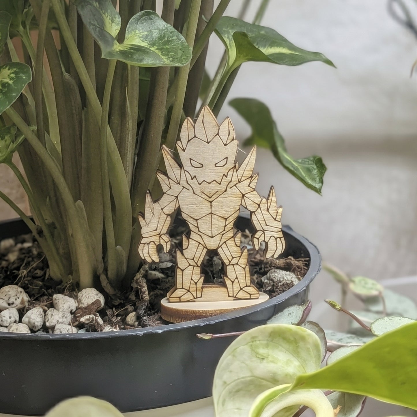 Back view of a crystal golem miniature of laser cut plywood held in hand. Highlights faceted crystal patterns and dark edges
