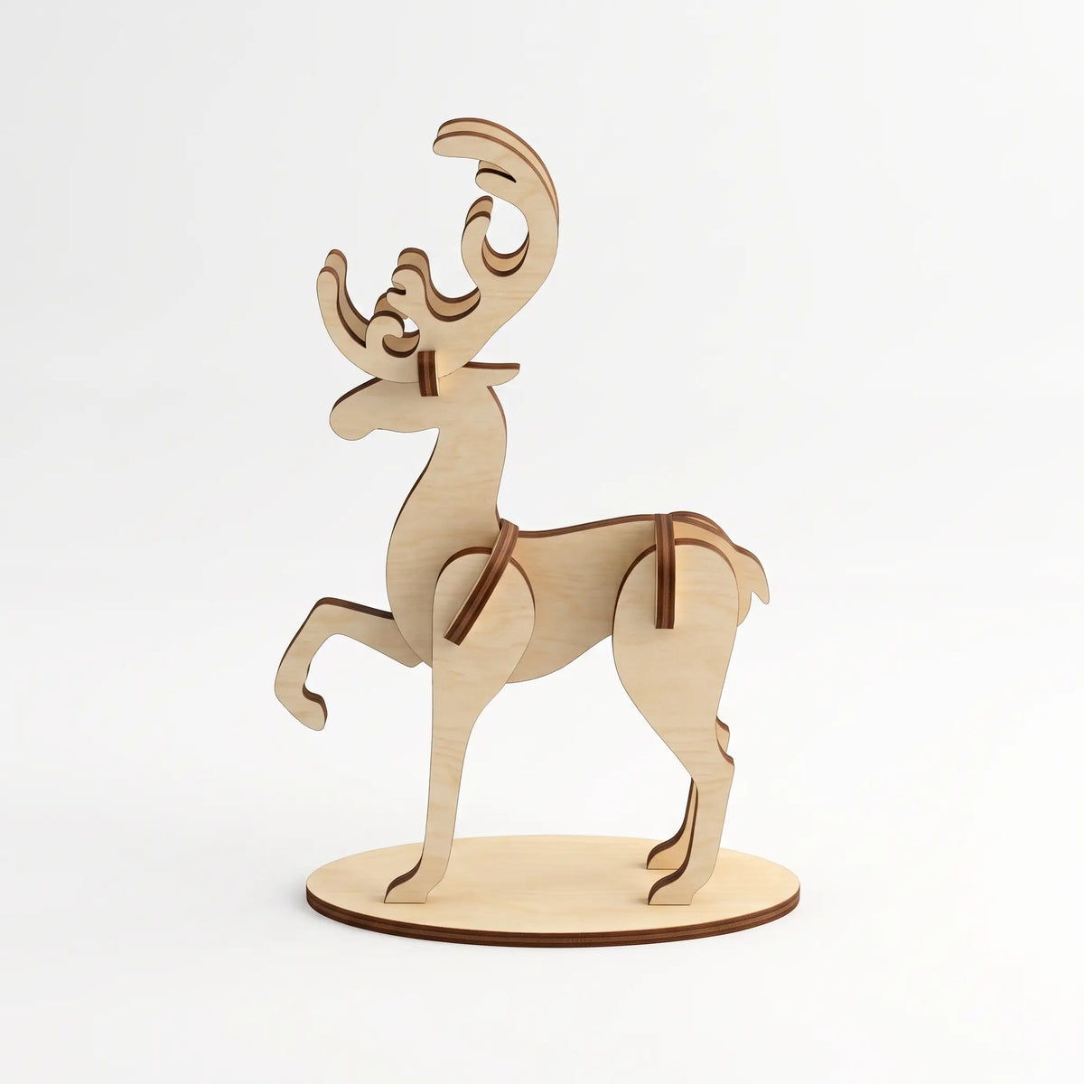 Side view of 3D laser cut plywood deer figurine with curved antlers standing on round wooden base over white background.