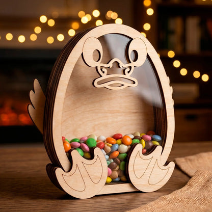 Laser cut plywood duck shaped candy box with a clear acrylic window filled with colorful sweets on a wooden table.
