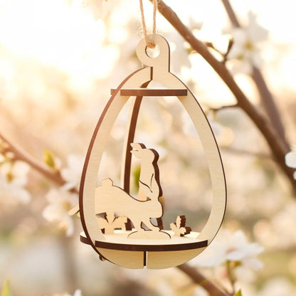 Laser cut plywood wooden 3D Easter egg ornament with a rabbit and foliage design inside, hanging by a string from a blooming white cherry tree branch in warm, soft sunlight, creating a springtime glow