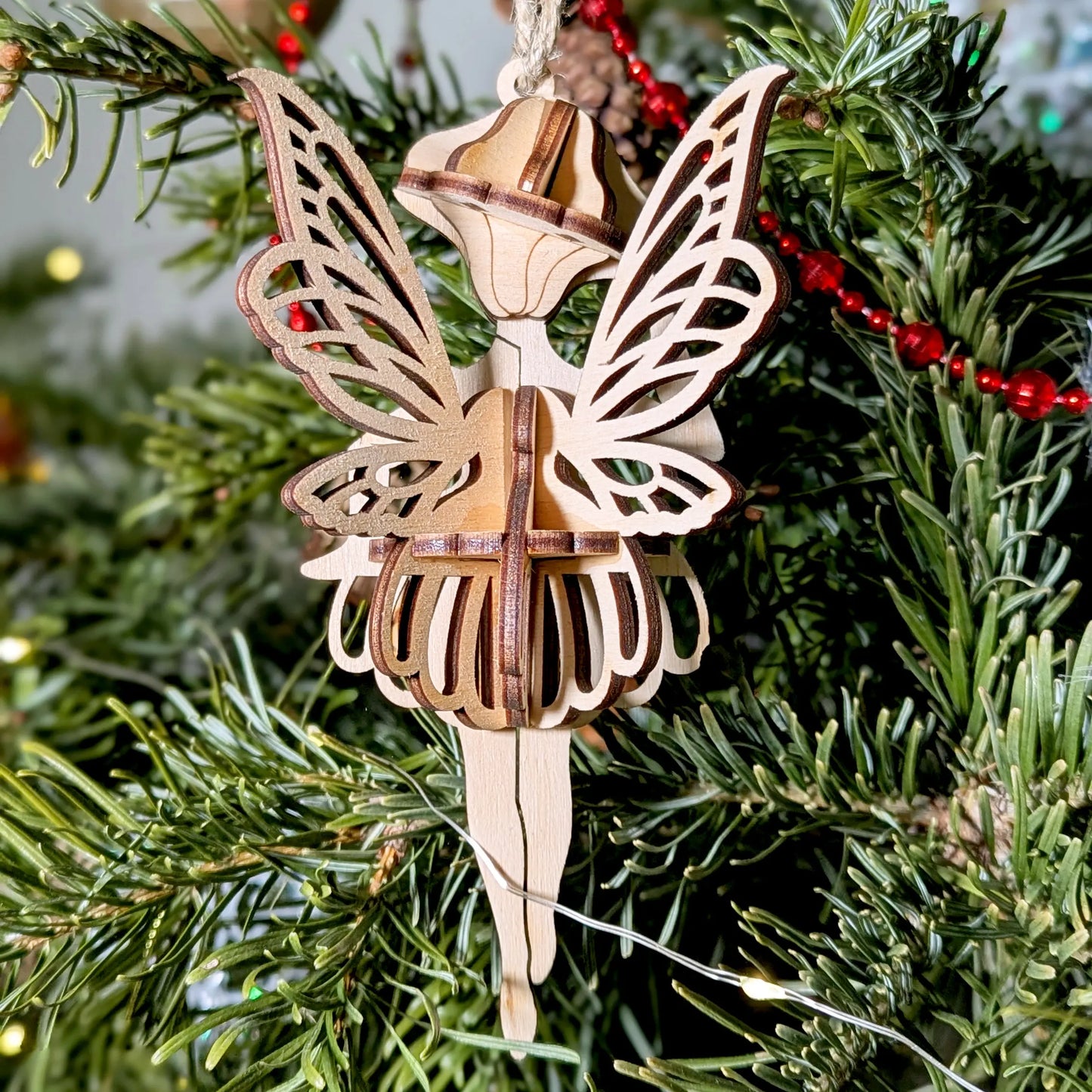 Laser cut plywood fairy showing layered 3D skirt and wings on a Christmas tree.
