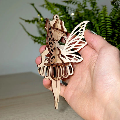 Side view of a 3D laser cut plywood fairy held in a hand, showing the interlocking slotted structure.