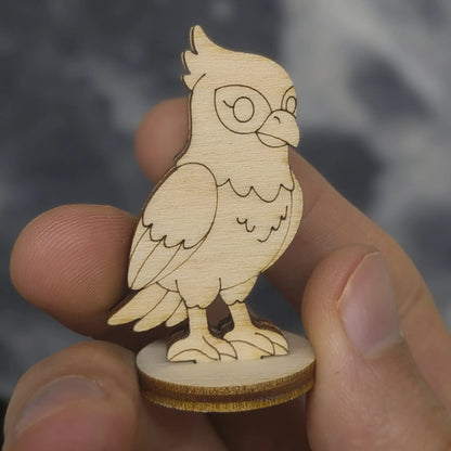 Hand holds a laser cut plywood falcon figurine for scale, showing detailed engraved wings, eyes, and sharp talons on a base