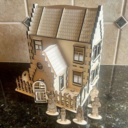 Laser cut plywood family house displayed on a dark counter with five miniature wooden family figurines standing out front.