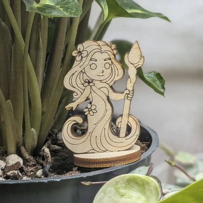 A laser cut plywood fantasy dryad figurine sits in a plant pot. Features a leafy hair crown and delicate engraved face
