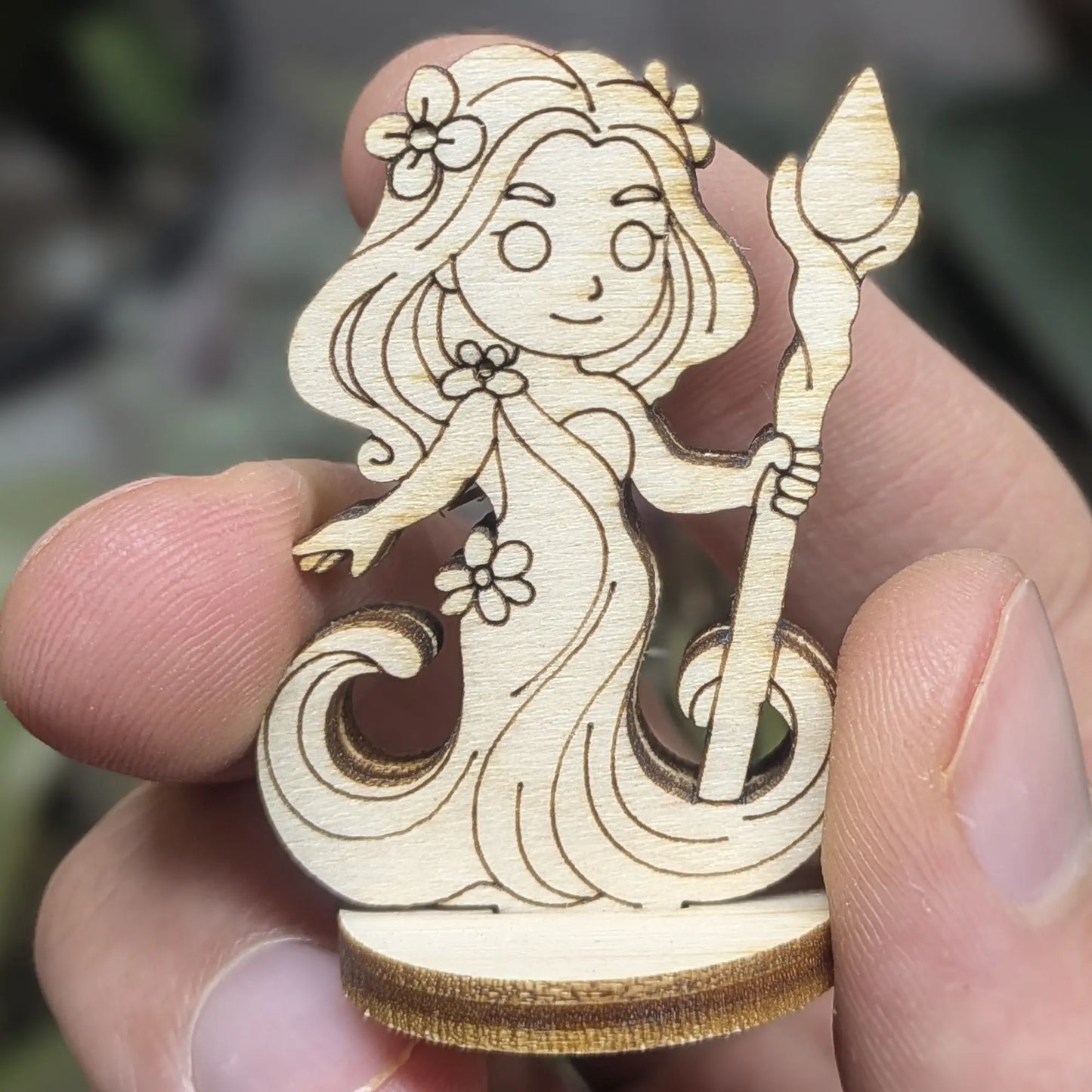 Hand holds a laser cut plywood forest dryad. Detailed front view shows the leafy hair crown and miniature tabletop scale