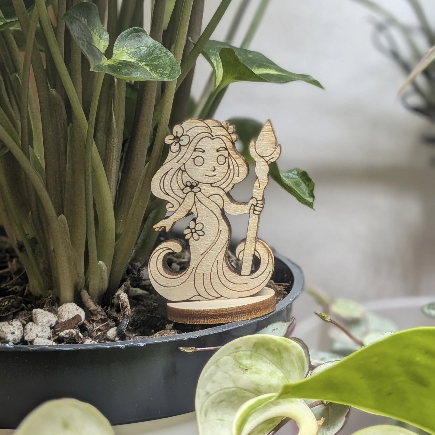 A laser cut plywood fantasy dryad figurine sits in a plant pot. Features a leafy hair crown and delicate engraved face