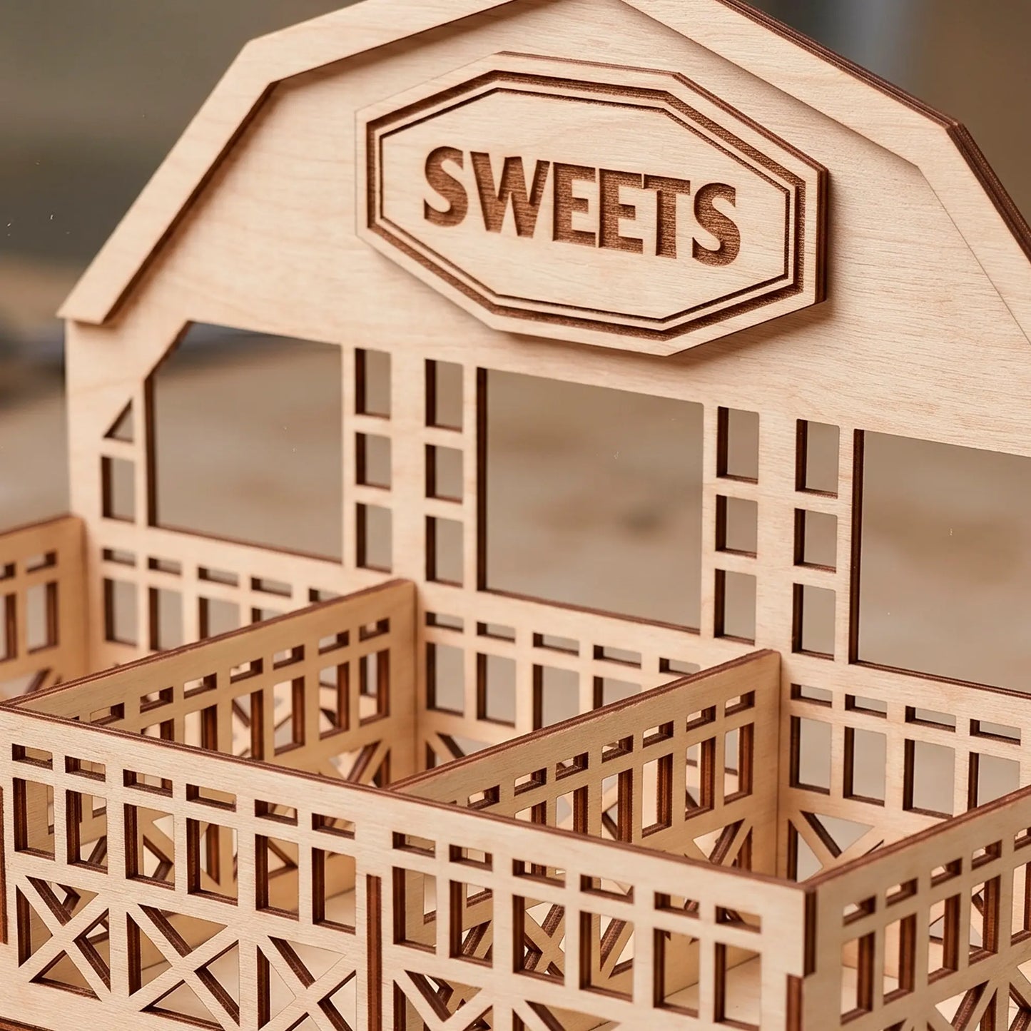 Close up of laser cut plywood barn display stand showing engraved Sweets sign, clean wood grain and precise fence details