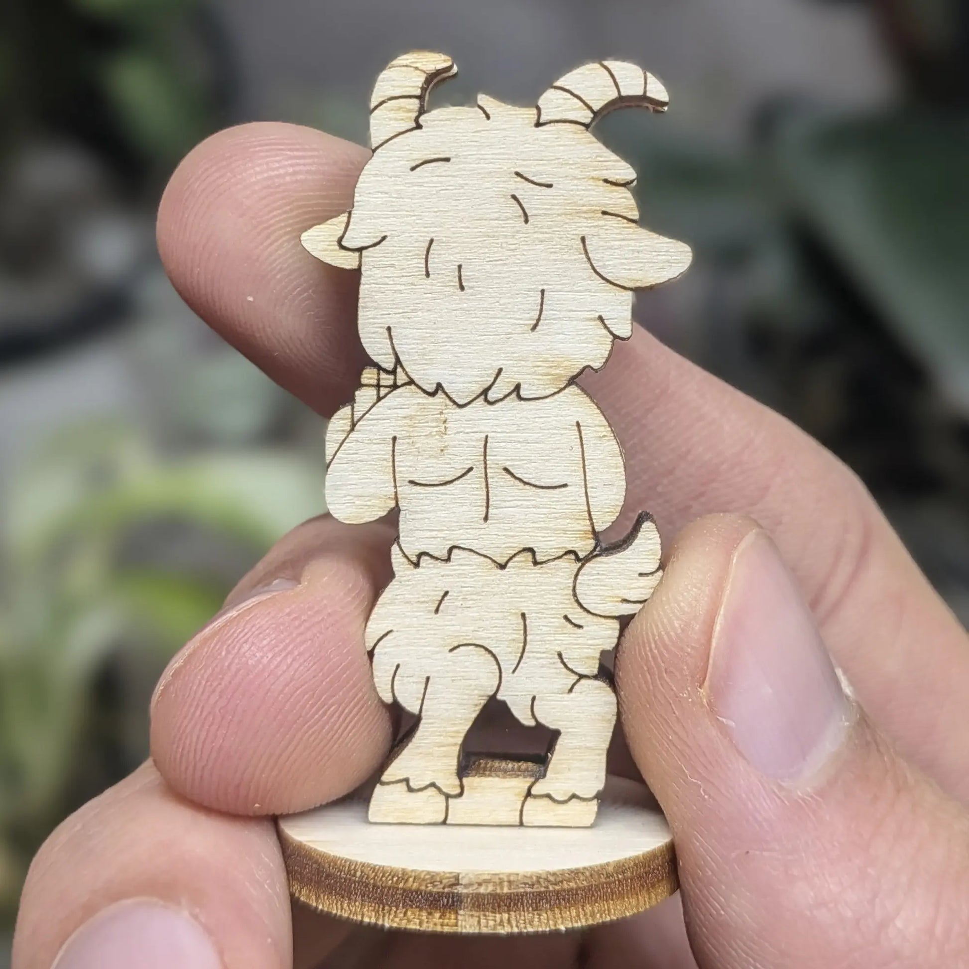 Back view of a laser cut plywood faun held in hand. Shows dark burnt edges, furry texture engravings, and a cute tiny tail.