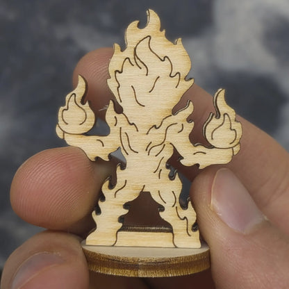 Back view of a laser cut plywood fire elemental held in hand. Highlights the dark burnt edges and natural wood grain finish