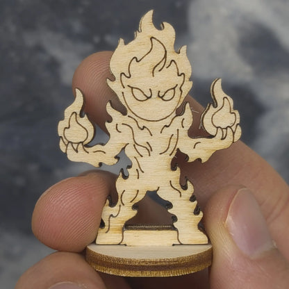 Hand holds a laser cut plywood fire elemental figurine. Detailed front view showing etched flame patterns and wood texture