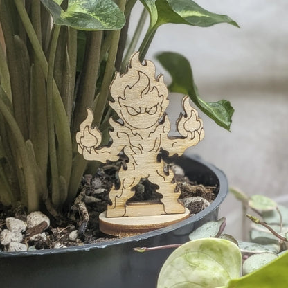 Fire elemental of laser cut plywood sits in a plant pot. Features engraved flame swirls and a tiered fire-shaped body on base