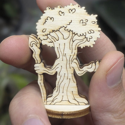 Back view of a laser cut plywood forest guardian tree held in hand. Highlights leafy engravings and dark burnt wood edges