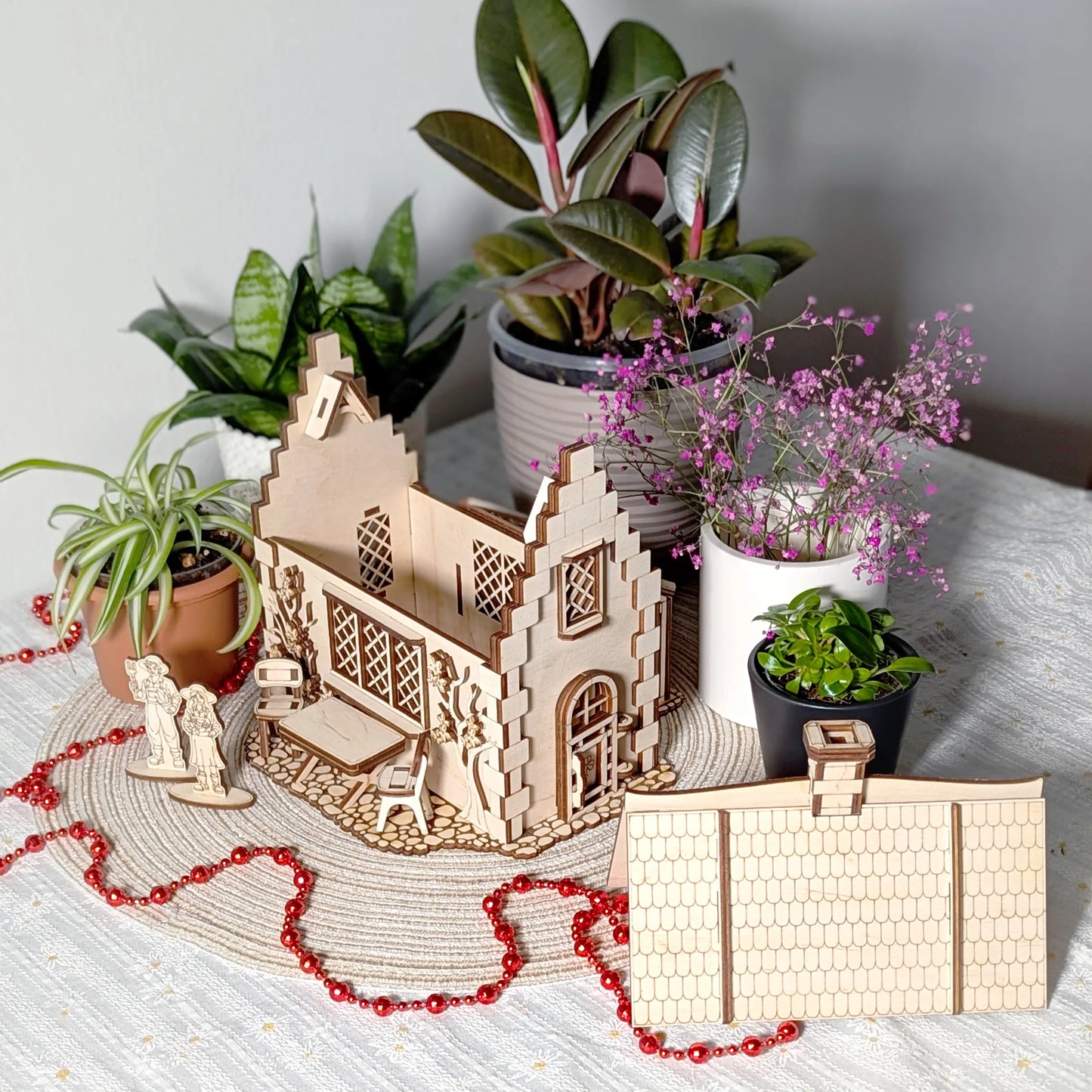 A laser cut plywood garden cottage model with its roof removed and placed alongside to reveal the open internal layouts.