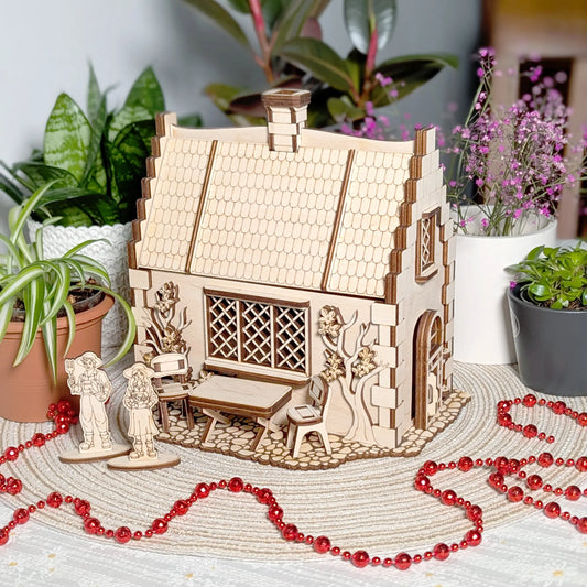 An aesthetic lifestyle shot of a laser cut plywood garden cottage model styled on a table with indoor plants and red beads.