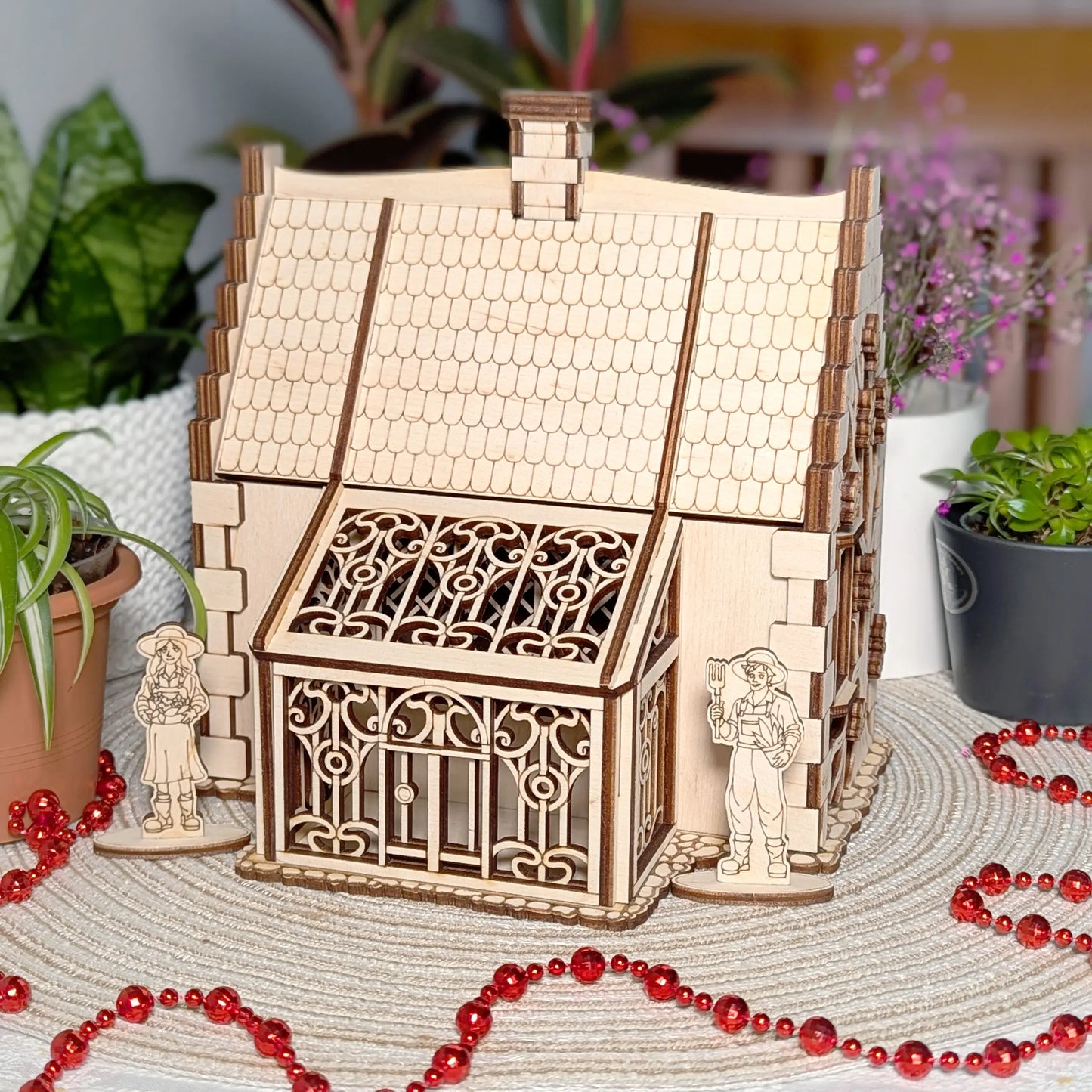 Front view of a detailed ornate greenhouse conservatory attached to a cozy laser cut plywood rustic garden cottage model.