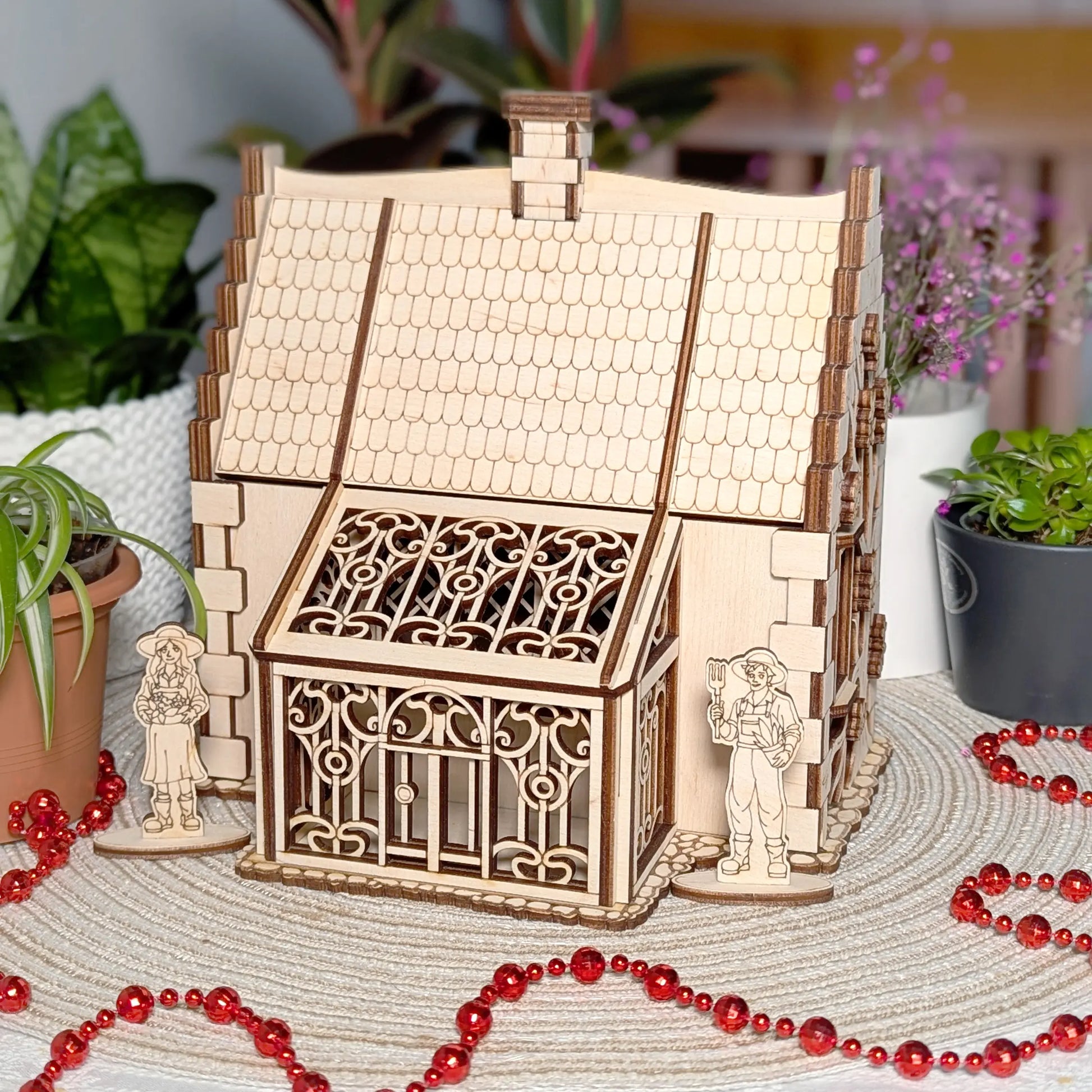 Front view of a detailed ornate greenhouse conservatory attached to a cozy laser cut plywood rustic garden cottage model.
