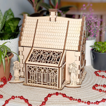 Front view of a detailed ornate greenhouse conservatory attached to a cozy laser cut plywood rustic garden cottage model.