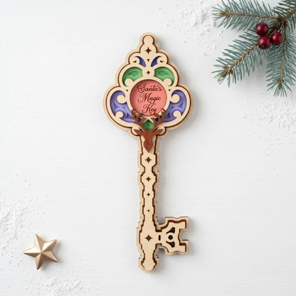 Colorful layered laser cut plywood Santa magic key ornament with deer head on white table with pine branch and gold star.