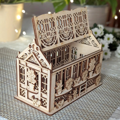 Open laser cut plywood greenhouse box with hinged roof lifted, showing hollow interior and detailed plant engravings.