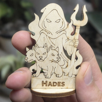 Hand holds a laser cut plywood Hades figurine for scale. Features an engraved crown, bident staff, and detailed robes