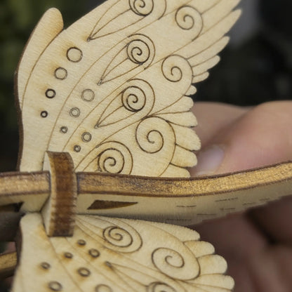 Close-up of wing details on a laser cut plywood bird. Shows precise engraved teardrops, swirls, and decorative dotwork