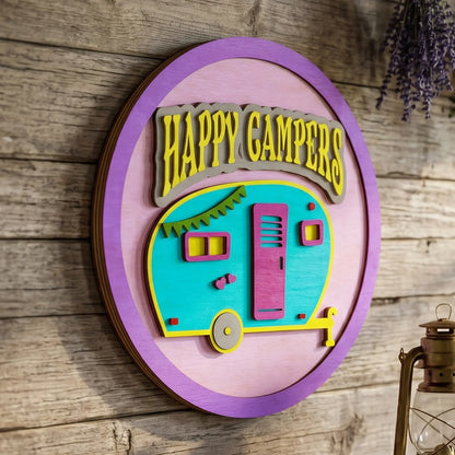 Side view of a layered laser cut plywood Happy Campers sign with a retro trailer on a rustic wall near a vintage lantern