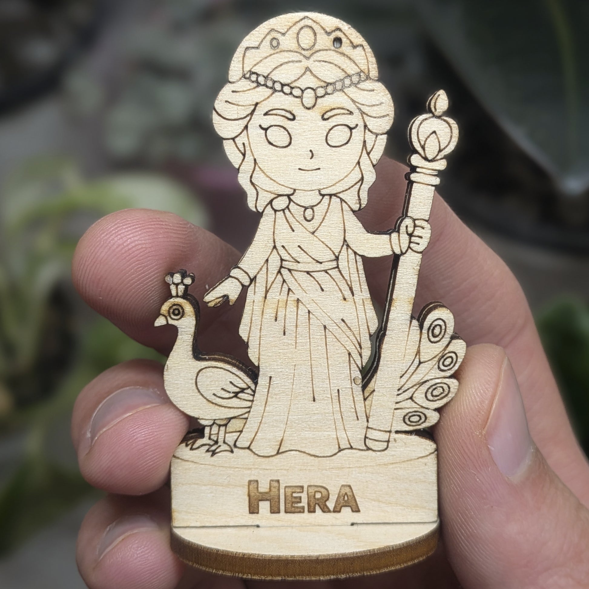 Hand holds a laser cut plywood Hera for scale. Detailed front showing the engraved crown, scepter, and royal Greek robes