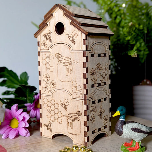 Close up of a laser cut plywood bee hive organizer box engraved with honey jars next to a miniature toy mallard duck.
