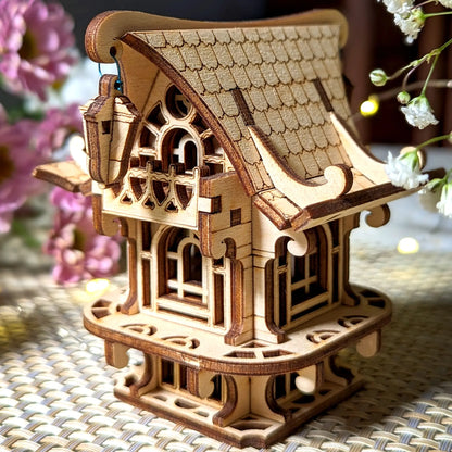Close-up of a laser cut plywood toy cabin featuring a tiny hanging lantern, layered tiled roof, and carved window frames.