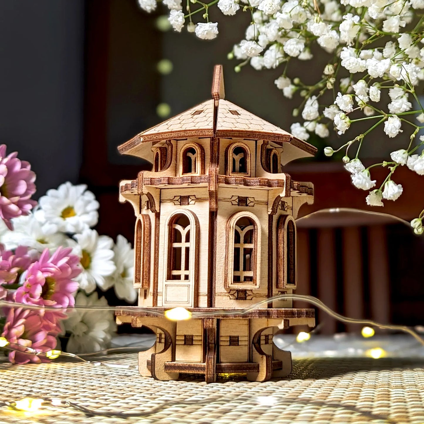 Intricate laser cut plywood garden tower displayed with flowers, highlighting its precise wooden craft and design.