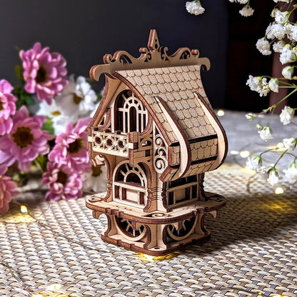 Ornate tabletop chalets puzzle of laser cut plywood showing a curved roof, tiny balcony, and bright spring flowers.
