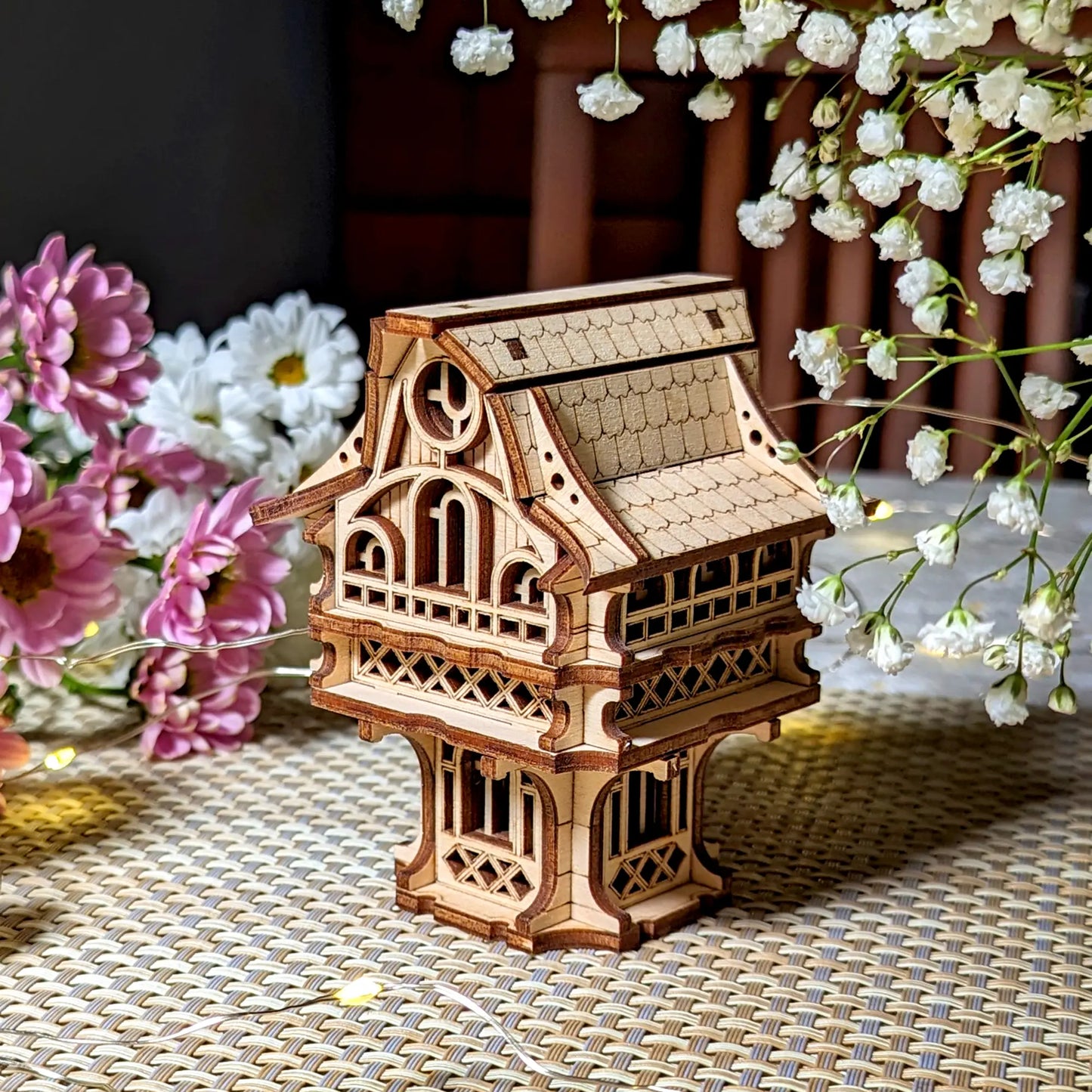 Detailed miniature gnome house of laser cut plywood, elegantly displayed among spring flowers and soft ambient lighting.