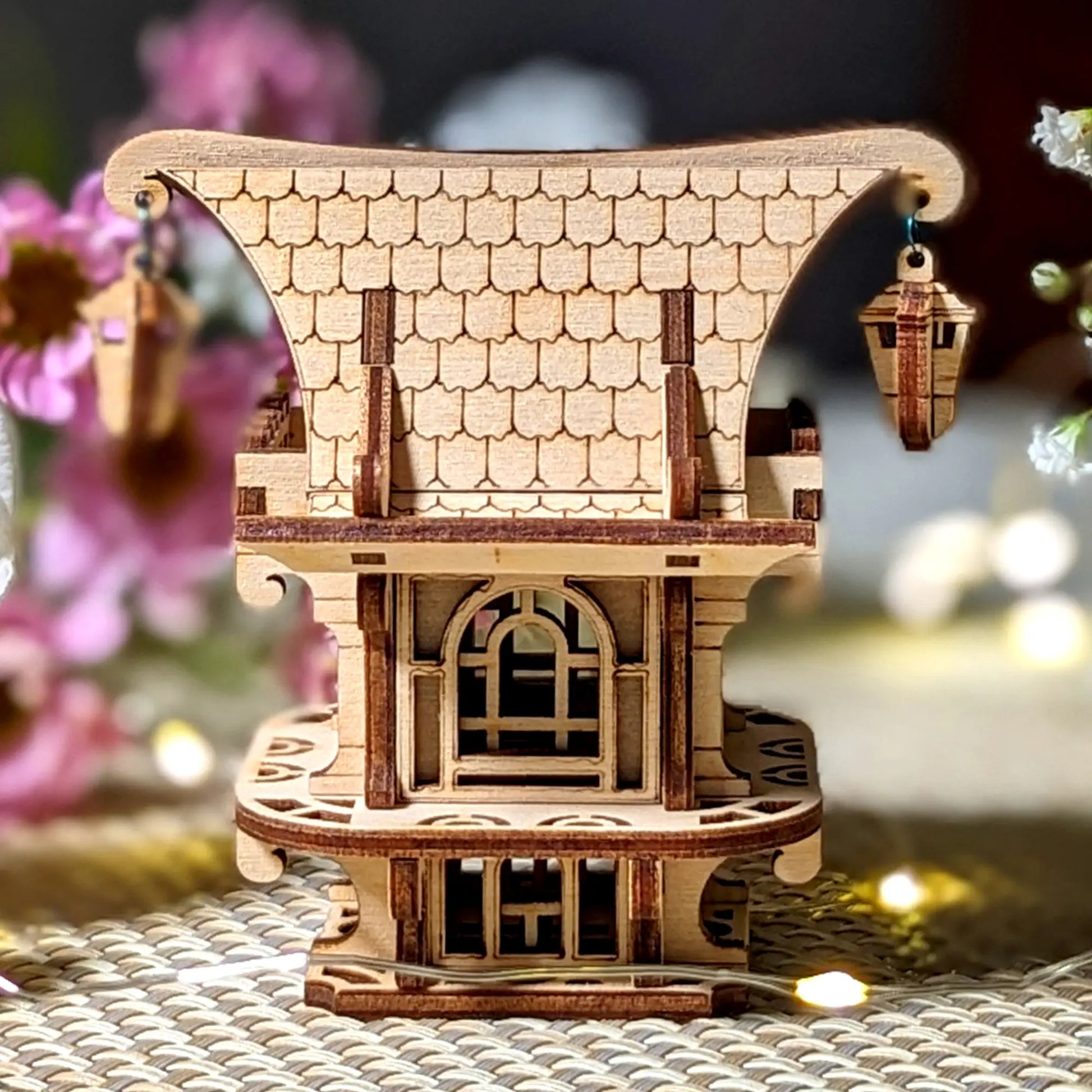 Back view of an intricate laser cut plywood fairy house, showing precise wood craftsmanship and roof structure.